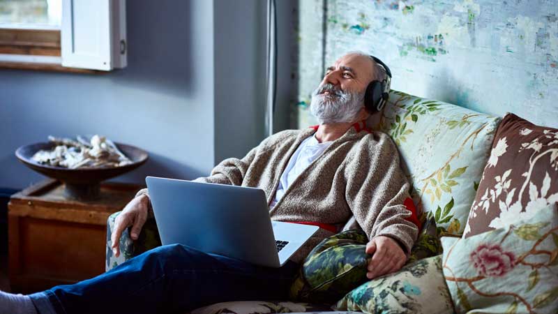 Older man relaxing on couch with headphones