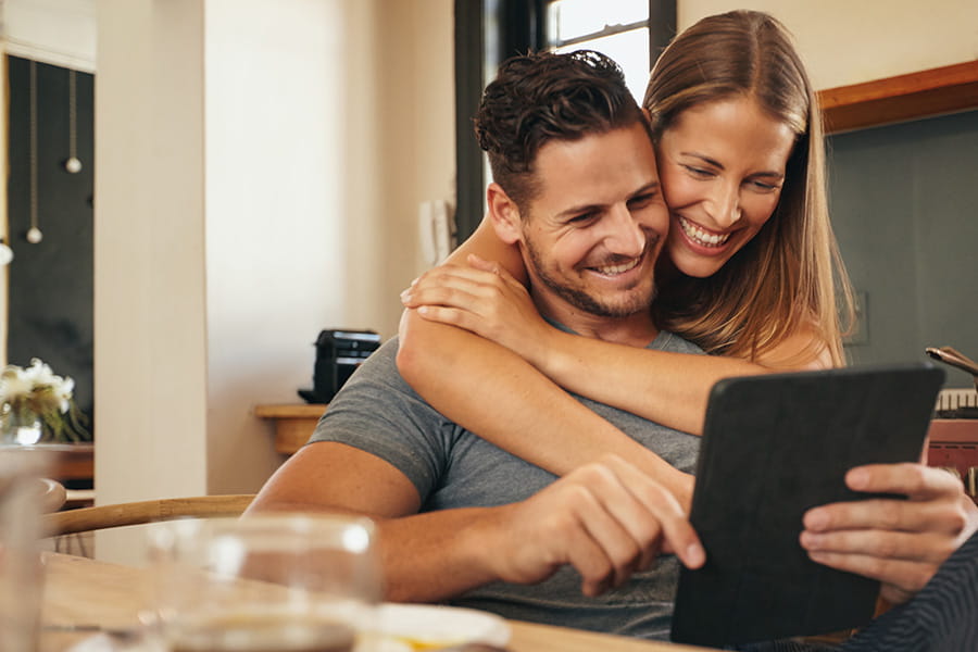 Young couple smiling looking at tablet together in kitchen