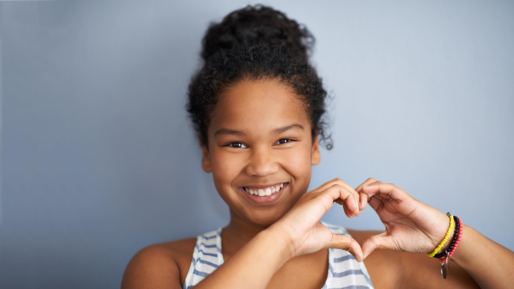 Young smiling girl making a heart with her hands