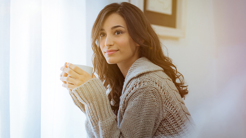 stress-free woman holds warm drink