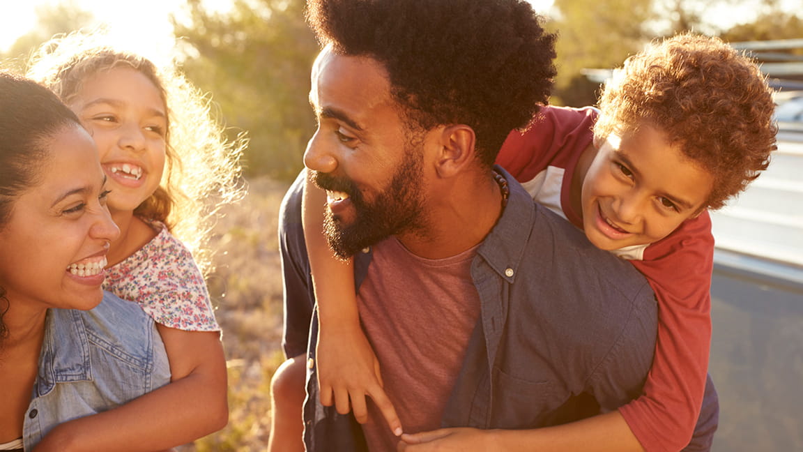 Cheerful woman holding on to boyfriends head while having piggyback ride  stock photo