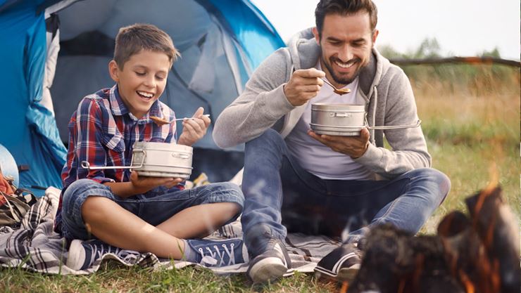 father and son eating at the campfire