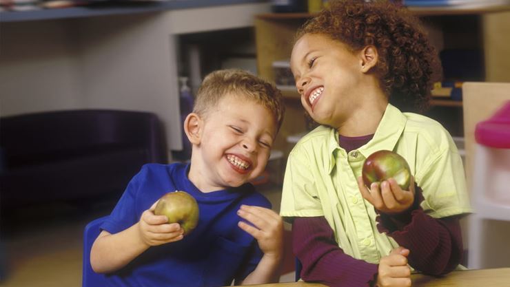 boys laughing while eating apples