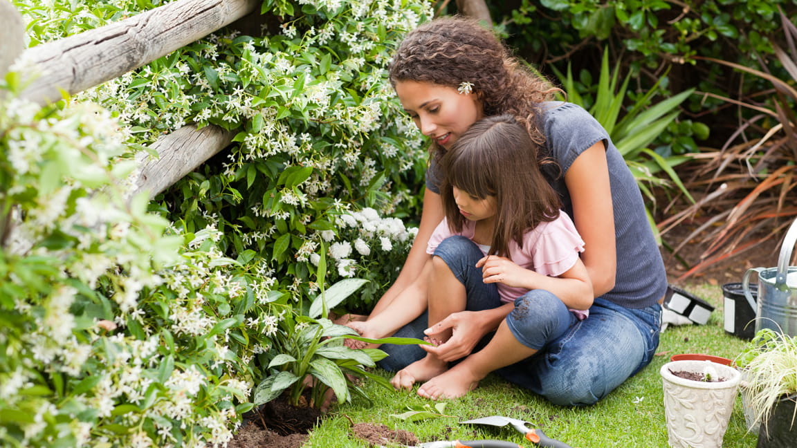 mother and daughter planting in garden