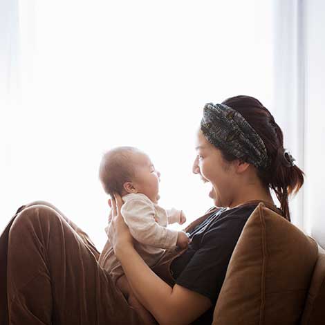 mom sitting in chair laughing with baby