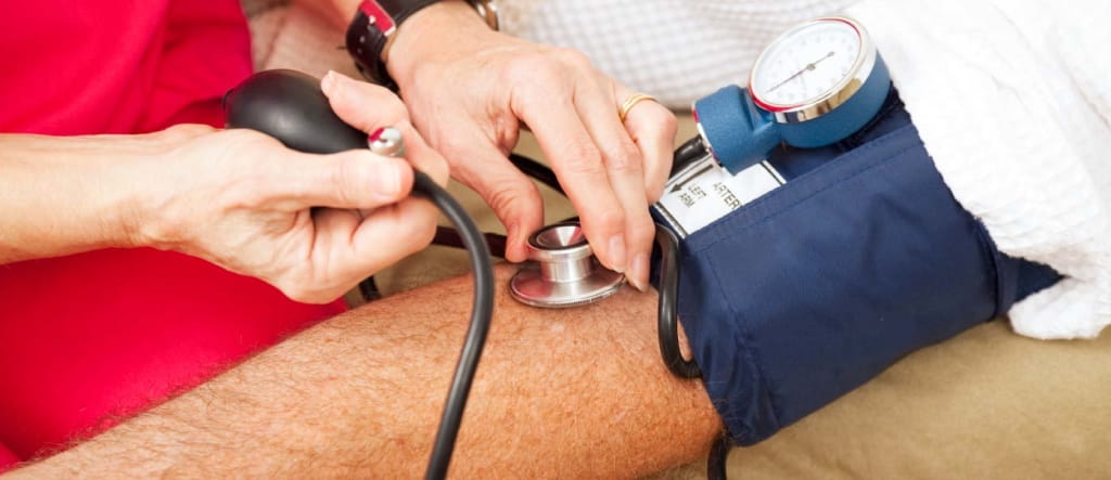 Woman taking man's blood pressure.