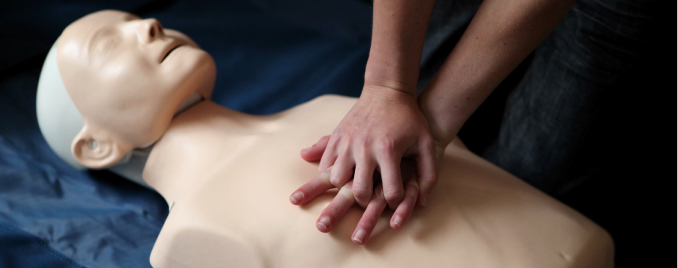 hands performing CPR on a mannequin