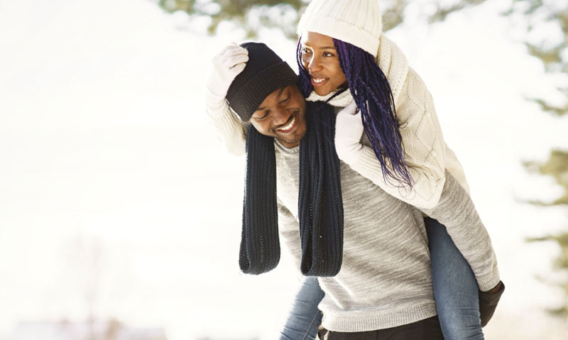 couple enjoys piggyback ride in snow couple enjoys piggyback ride in snow