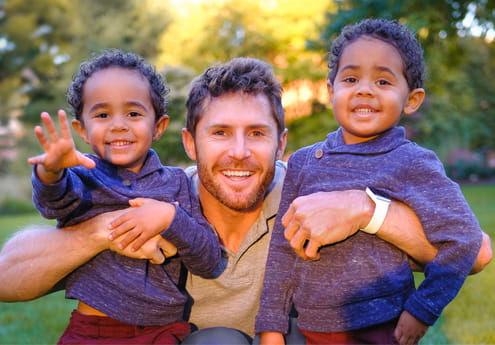 Father and twin sons outside smiling