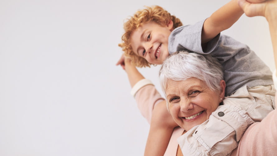 grandmother with grandchild on shoulders, smiling down at camera