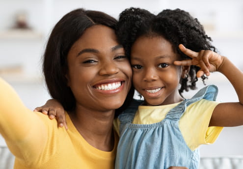 mother and daughter, cheek to cheek, smiling for camera