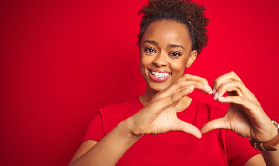 Woman smiling and holding her hands in the shape of a heart