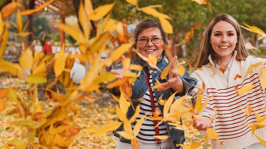Mother and daughter throwing leaves in the air