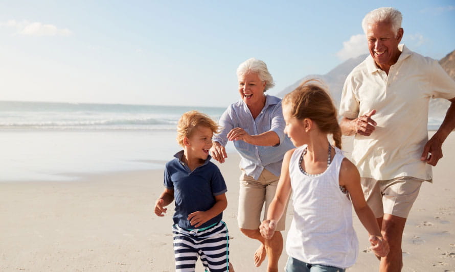 multigenerational family runs on beach on summer day
