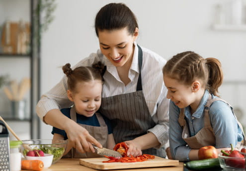 Woman and two girls cutting up a tomato