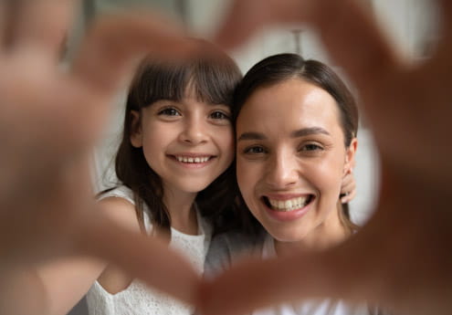 Mom and kid framed by heart hands