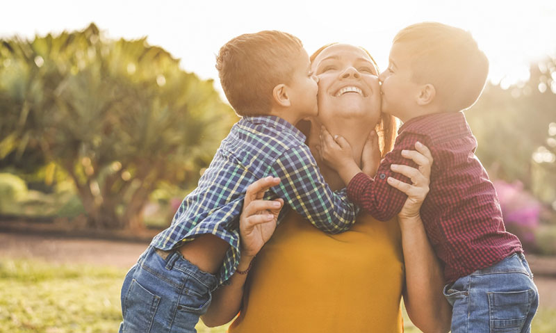twins boys kiss mother on cheek at sunset twins boys kiss mother on cheek at sunset