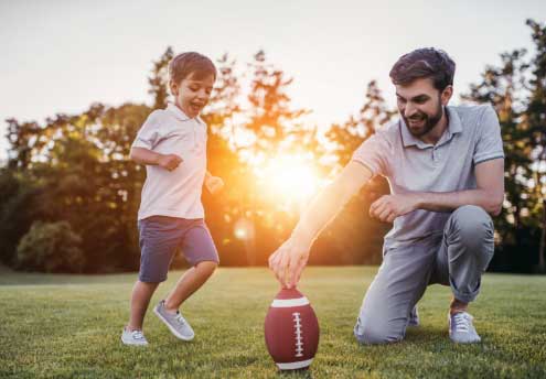 dad and young son playing football