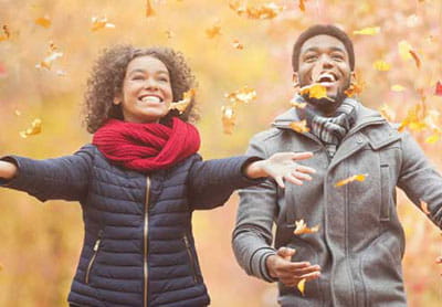 woman and man playing in autumn leaves