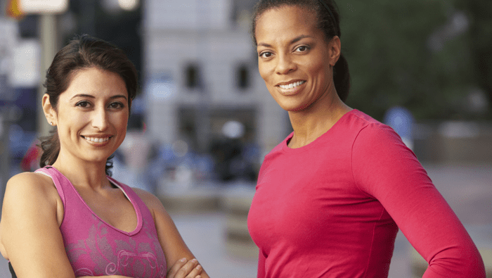 two women in workout clothes smiling at the viewer