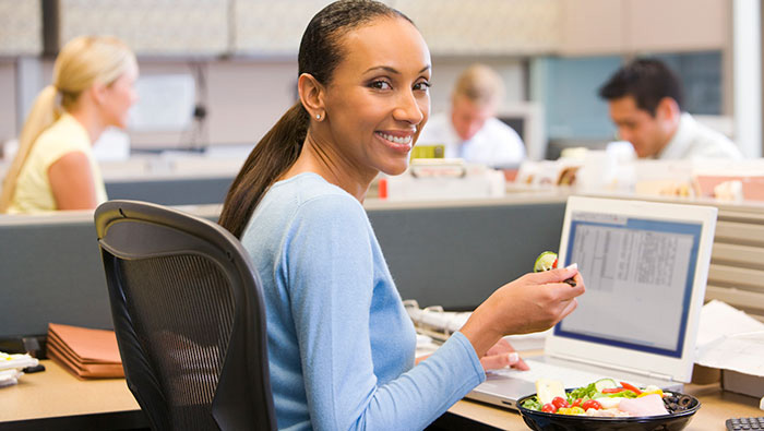 business woman eating lunch at her desk while working