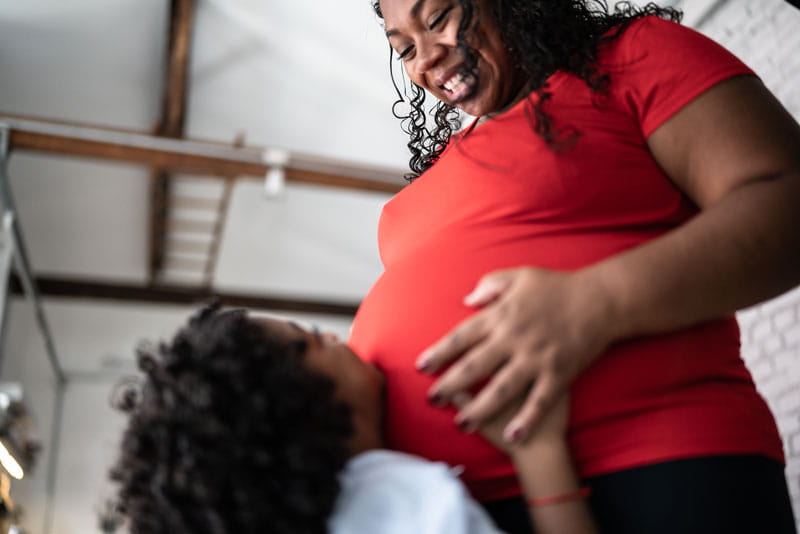 pregnant mother smiling down at her son