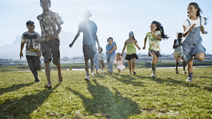 children running across a grassy field