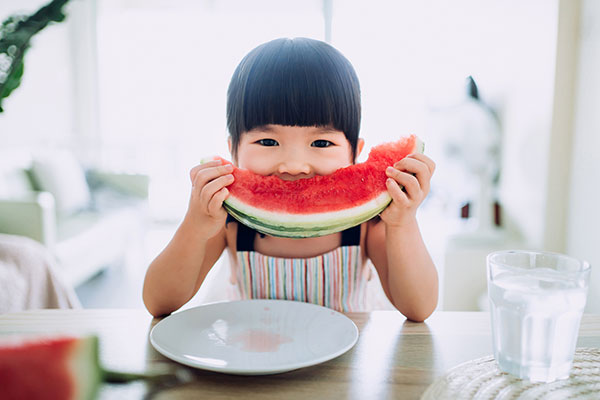 Asian toddler eating watermelon