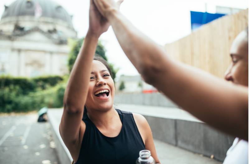 Two women giving a high five outside