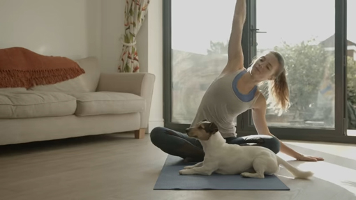 Habit Coach introduction video screenshot of young women doing yoga with dog present.