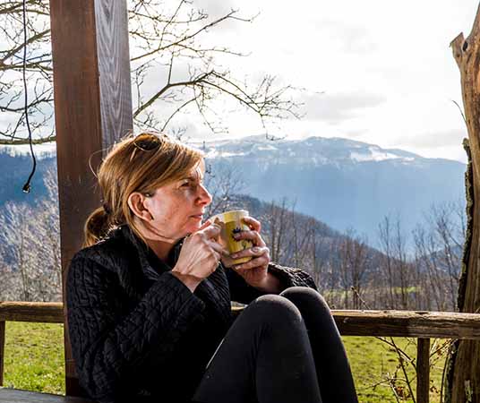 Mature women drinking coffee on porch with mountains in the background