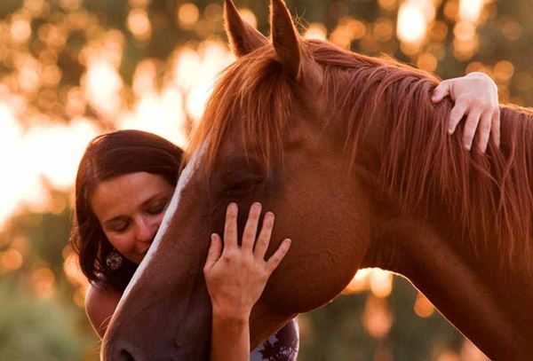 women hugging a brown horse