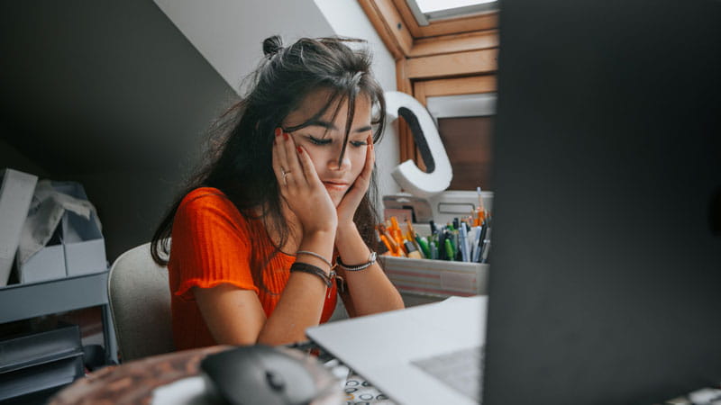 female teenager feeling stressed studying at home