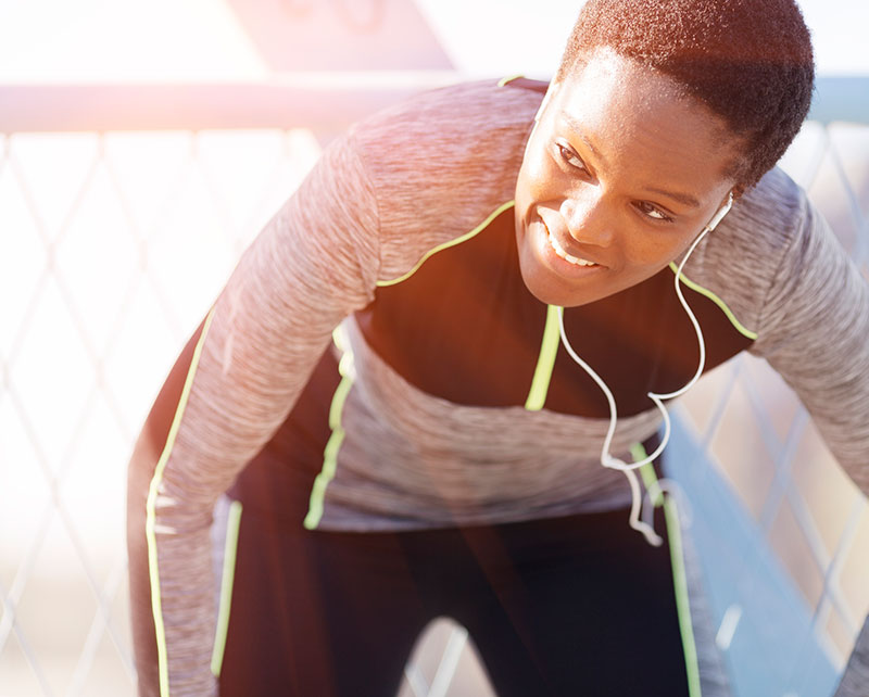 woman with headphones running outdoors catching her breath