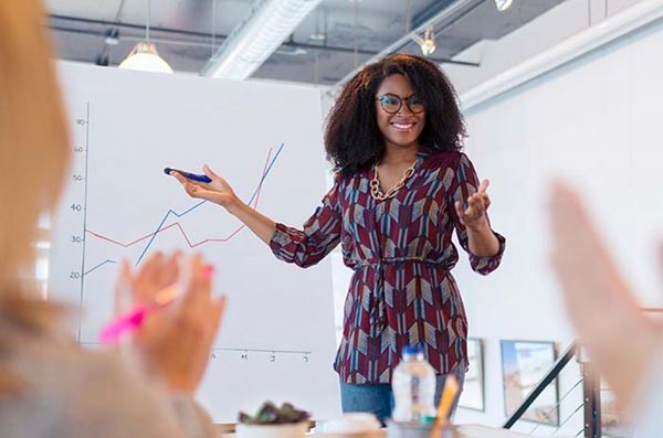 Woman presenting line graph to clapping team