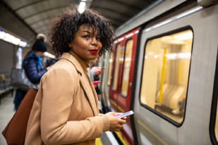 woman holding her phone about to board a train in underground station