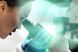 stock photo of female medical worker looking in microscope