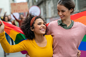 two young women at parade holding ride flag