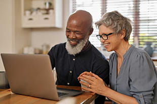 Smiling couple on laptop in kitchen