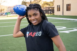 young teen female smiling while throwing a blue football