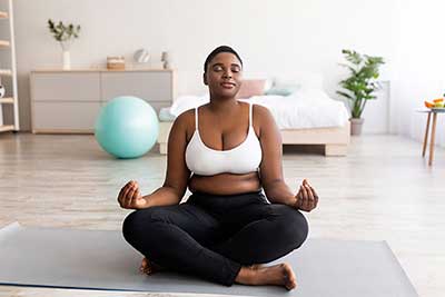 woman meditating on yoga mat at home