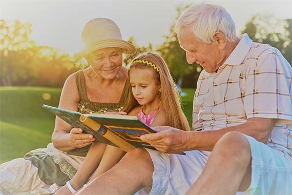 grandparents with granddaughter reading story from a book