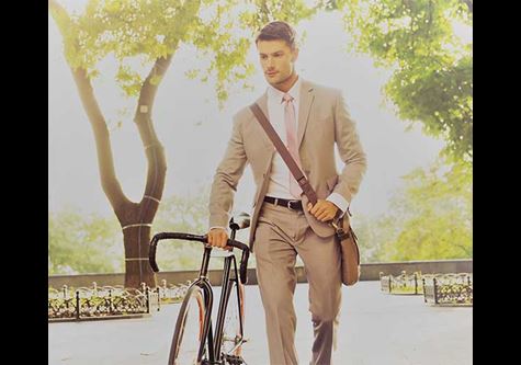 Man in suit walking while pushing bicycle