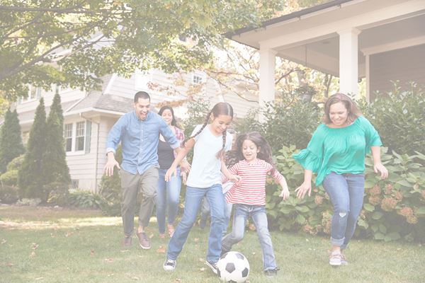 Multi-generational family playing soccer in their front yard