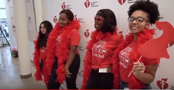 Young girls posing in front of banner with wearing red boas