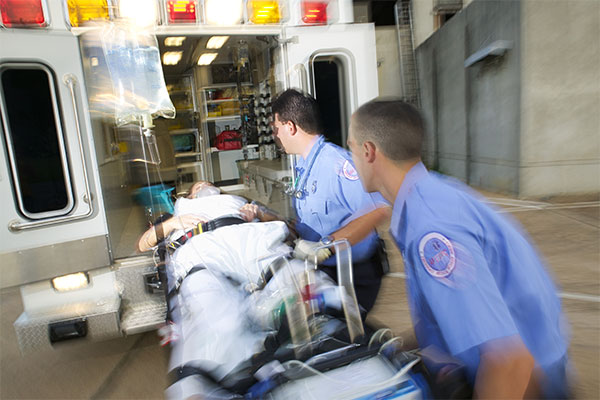 Blurred image of two EMTs moving a patient into an ambulance
