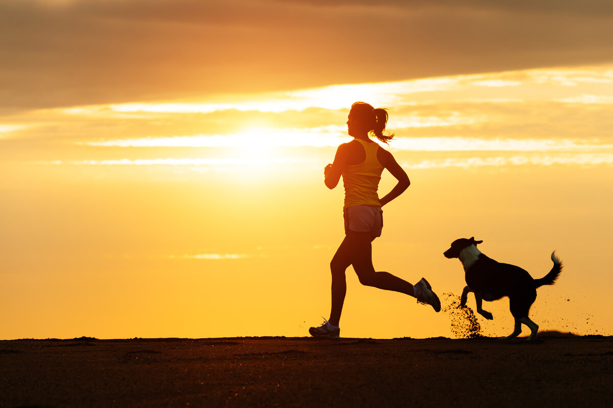 woman jogging at sunrise with her dog