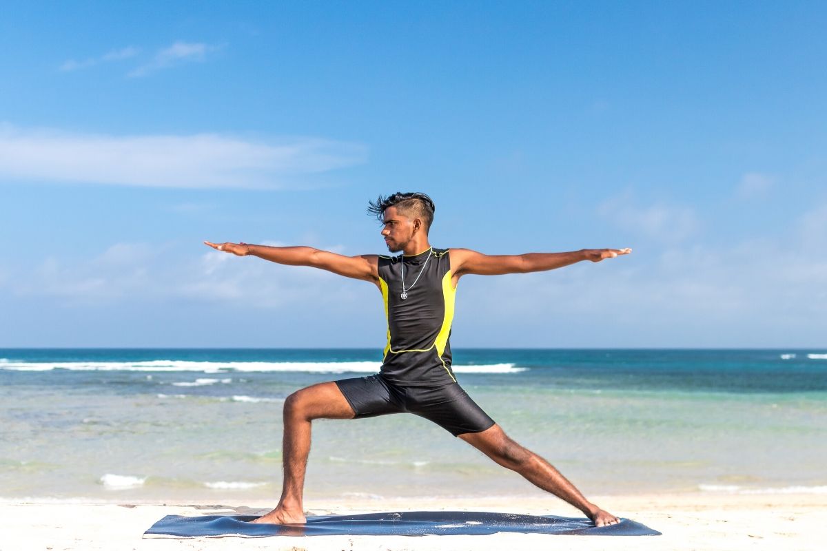 man doing yoga on a beach