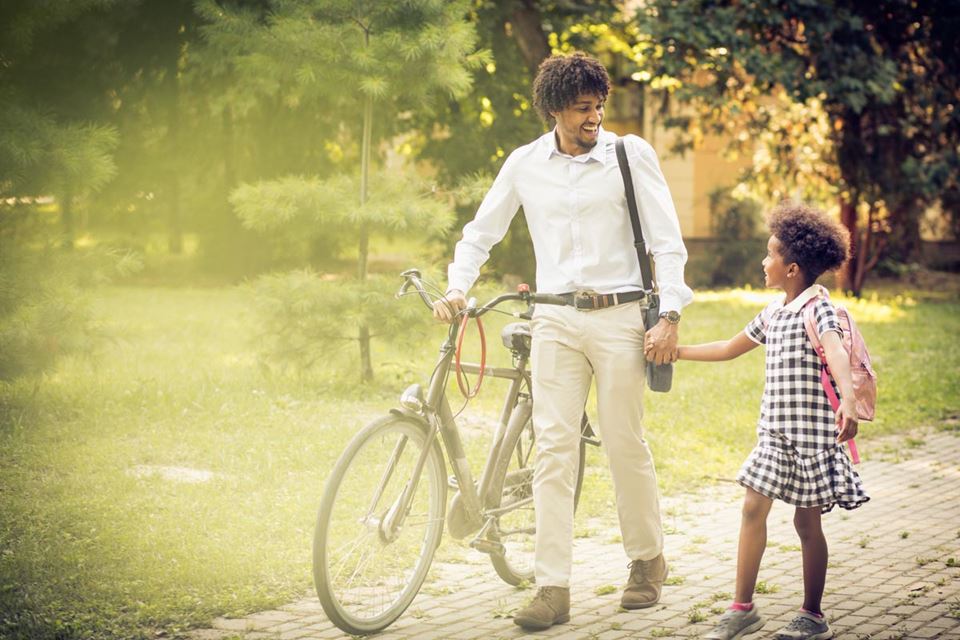 dad walking with bike holding his daughter's hand