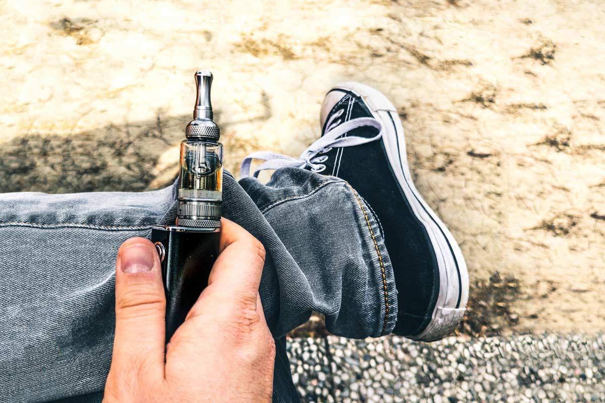 person wearing sneakers holding a vape pen